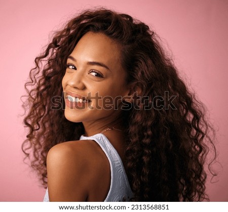 Health, hair care and portrait of a woman in a studio with a natural, long and curly hairstyle. Happy, smile and brunette female model with beauty keratin salon treatment isolated by pink background.