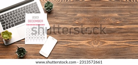 Calendar for December 2023, modern laptop and mobile phone on wooden background with space for text