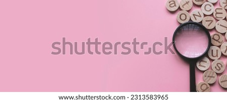 Concept of learning english, searching for word, and information. English alphabet letter and magnifying glass. Pink background with copy space. Royalty-Free Stock Photo #2313583965