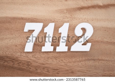 White number 7112 on a brown and light brown wooden background.