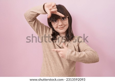Little hispanic girl wearing glasses smiling making frame with hands and fingers with happy face. creativity and photography concept. 