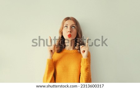Portrait of wondering surprised young woman pointing her fingers up on white background, blank copy space