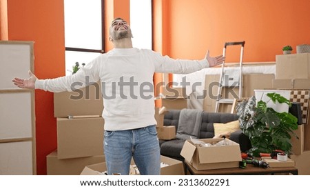 Young hispanic man smiling confident standing with arms open at new home Royalty-Free Stock Photo #2313602291