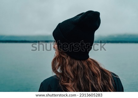 girl with a hat overlooking the tranquility of the lake on a winter day Royalty-Free Stock Photo #2313605283