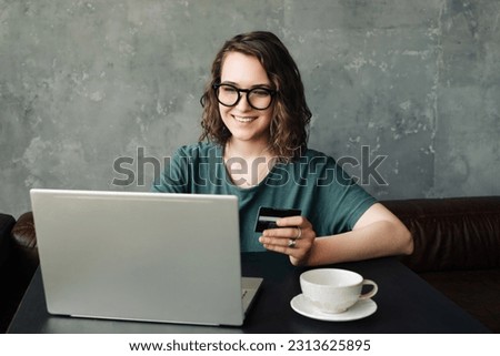 Seamless Shopping Experience: Young Woman with Credit Card Engaged in Online Transactions, Utilizing Laptop Computer for Convenient and Secure Online Shopping Royalty-Free Stock Photo #2313625895