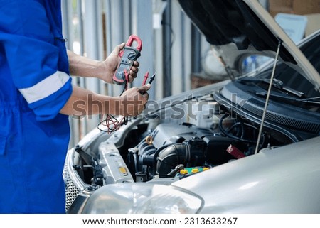 Professional mechanic checking customer's car's electrical system brought in for repair, all types of auto specialists, expert car repairs and certified auto repair centers. Royalty-Free Stock Photo #2313633267