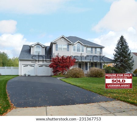 Real Estate Sold (another success let us help you buy sell your next home) sign suburban mcmansion style home autumn day residential neighborhood blue sky clouds USA