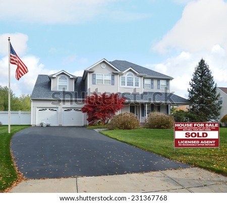 Real Estate Sold (another success let us help you buy sell your next home) sign suburban mcmansion style home autumn day residential neighborhood blue sky clouds USA