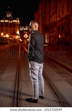 male businessman in black shirt in night city under street light