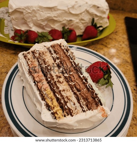A picture of a slice of ice cream cake with strawberry on the side