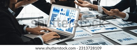 Panorama shot analyst team utilizing BI Fintech to analyze financial report with laptop. Businesspeople analyzing BI data dashboard displayed on laptop screen for business insight. Prodigy