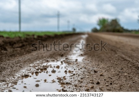 low angle view of a mud on a gravel road from a recent rainstorm. Royalty-Free Stock Photo #2313743127
