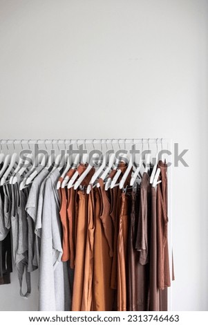 cloth hanging in rank shirts trousers pants fashion collection white background moody light vertical