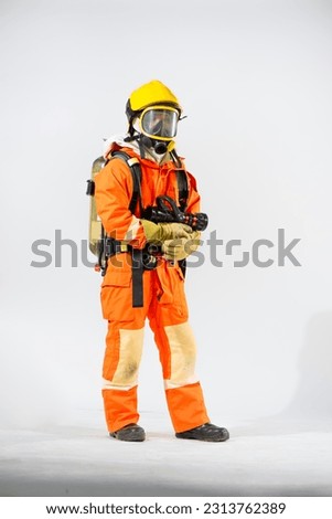 Professional firefighter standing holding fire hose with both hands and looking to the camera on white background.