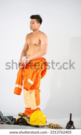 Professional firefighter standing with tired expression and have important equipment on the floor on white background.