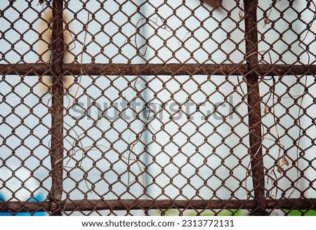 An old rusty iron fence made of mesh on a light background. The image of unfreedom, obstacles, the impossibility of movement and development.