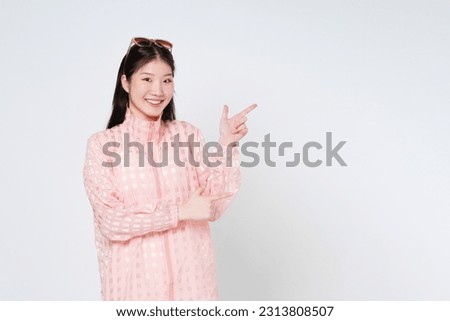 Young woman pointing to empty copy space isolated on white background.