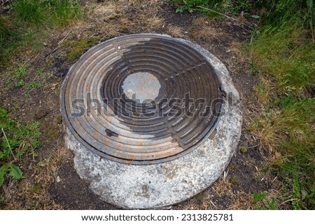 The manhole of the sewer well on a summer day