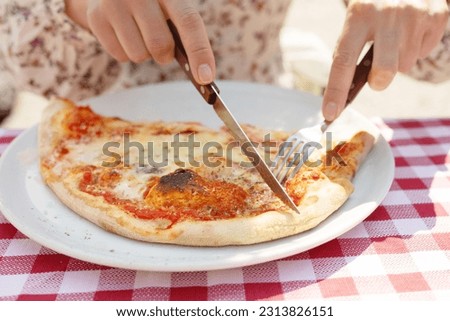 Cutting pizza into pieces. Woman cuts pizza close-up.