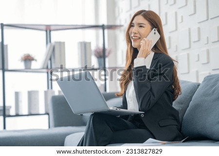 Image of a young beautiful Asian Business woman smiling while working with a laptop and talking to work doing math finance on an office desk, tax, report, accounting, statistics, and research concepts