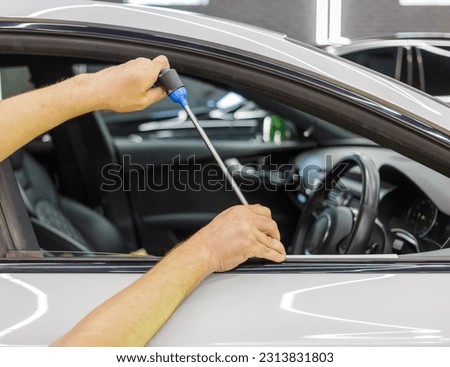 A specialist repairs a dent on the car body without painting. PDR. Process of paintless dent repair on car body. The mechanic at the auto shop with tools to repair dents in car body. Body repair. Royalty-Free Stock Photo #2313831803