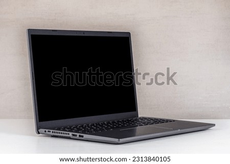 black mock-up on a laptop screen on a white table against a gray wall close-up