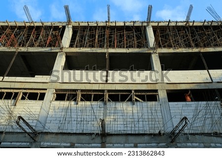 Low Angle View, a building that is just under construction, concrete steel as the structural bones are still surfacing.