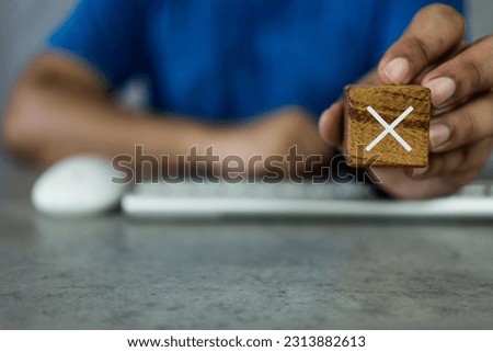Concept of negative decision making or choice of rejection. Man show a cross mark x on wooden cube. White cross sign on the edge of a wooden cube. Yes or no choice symbol. Copy space.