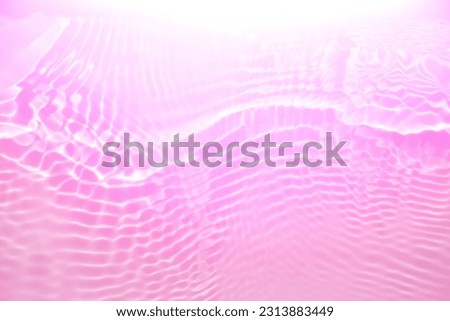 Purple water with ripples on the surface. Defocus blurred transparent pink colored clear calm water surface texture with splashes and bubbles. Water waves with shining pattern texture background