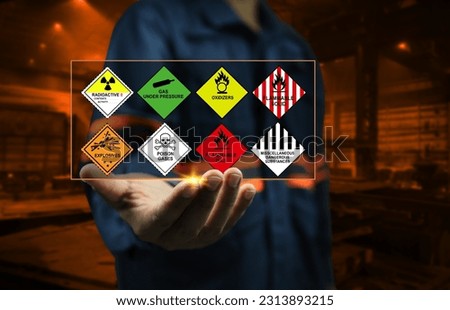Industrial factory safety officers hold chemical hazard warning signs in their hands to remind close workers to be aware of the dangers of chemicals in dangerous goods transport and handling concept. Royalty-Free Stock Photo #2313893215