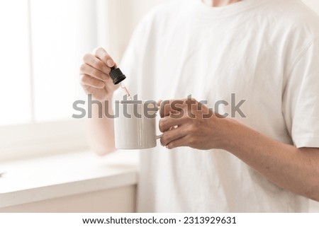 A man pours liquid into a cup with a dropper. Royalty-Free Stock Photo #2313929631