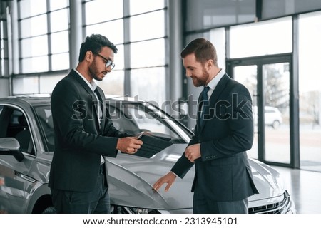 Using graphic tablet. Man is consulting the customer in the car showroom.