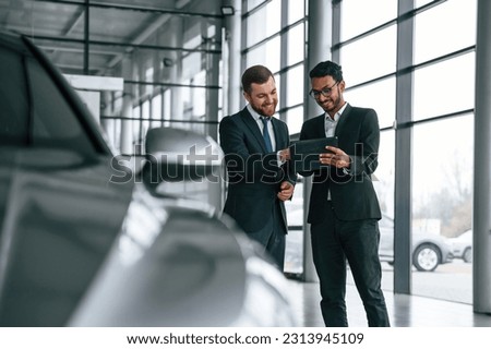 Checking quality of the vehicle. Man is consulting the customer in the car showroom. Royalty-Free Stock Photo #2313945109