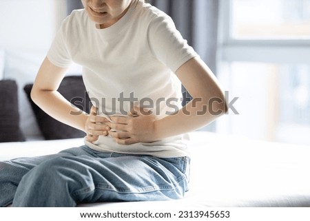 Asian teenager girl suffering from abdominal pain,gastritis,peptic ulcer disease,young woman with stomach ache,symptom of gastrointestinal disorders,stomach ulcer,gastric problem,health care,medical Royalty-Free Stock Photo #2313945653