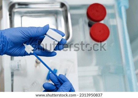 Gynecologist is holding flask for cytology Pap smear test in hands. Gynecological cytology Pap smear test and cytobrush in hands of gynecologist