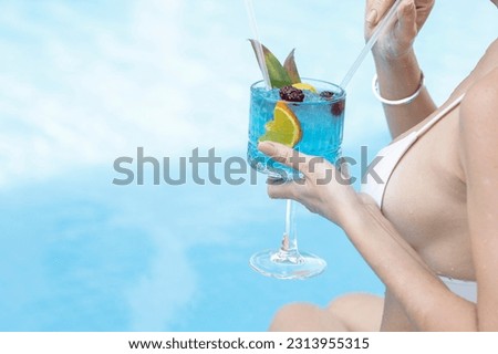 woman drinking cocktail by the pool