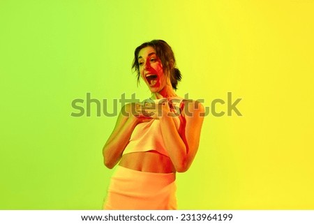 Birthday gift. Image with gorgeous woman standing with surprised face and open mouth over pink studio background in neon light. Concept of beauty, youth, human emotions, dreams, hobby, ad