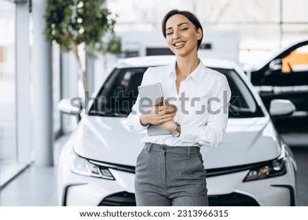 Young saleswoman with tablet in a car showroom Royalty-Free Stock Photo #2313966315