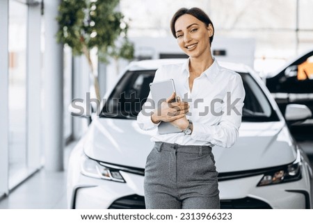 Young saleswoman with tablet in a car showroom Royalty-Free Stock Photo #2313966323