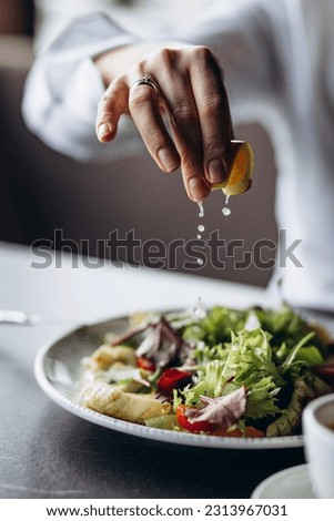 Woman squizing lemon on the salad