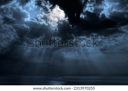 Nocturnal photo composition with moon, clouds, light beams and sea