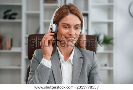 In the call center. In headphones. Woman in business formal clothes is working in office.