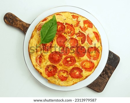 A captivating top view of a plate or pan showcasing scrambled eggs or tortilla with vibrant tomatoes and zucchini. The yellow surface of the omelet beautifully contrasts with the red tomatoes.