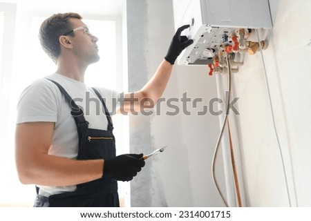 Professional plumber checking a boiler and pipes, boiler service concept. Royalty-Free Stock Photo #2314001715
