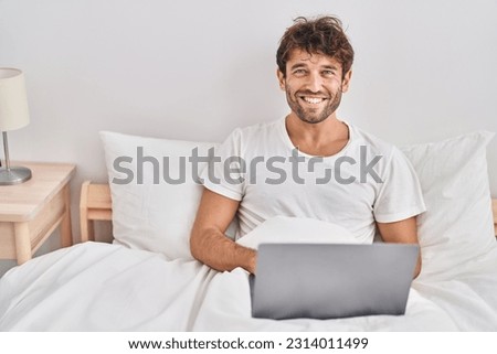 Young man using laptop sitting on bed at bedroom