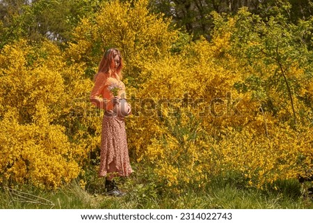 Young pregnant woman touching her belly and smelling flowers.Pregnancy, maternity, preparation and expectation concept.Beautiful tender mood photo of pregnant woman. Young mom.                        
