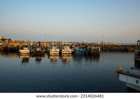 Six fishing boats anchored in a row on the calm sea in the morning at sunrise. (The Korean letters on the back of the ships indicate the port of the ship-Jeju)