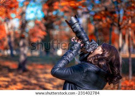 brunette young woman photographer taking pictures on an autumn day in park, nature