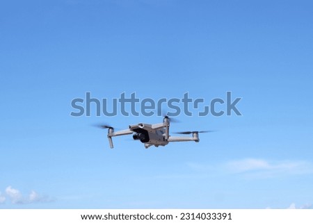 
Drone flying with rotating wheels in blue sky on sunny day. View from below.