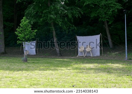 A view of a temporary shooting range prepared for an archery and crossbow competition with targets made out of rolled hay on wooden stands with the background being a cloth hanging from two sticks Royalty-Free Stock Photo #2314038143